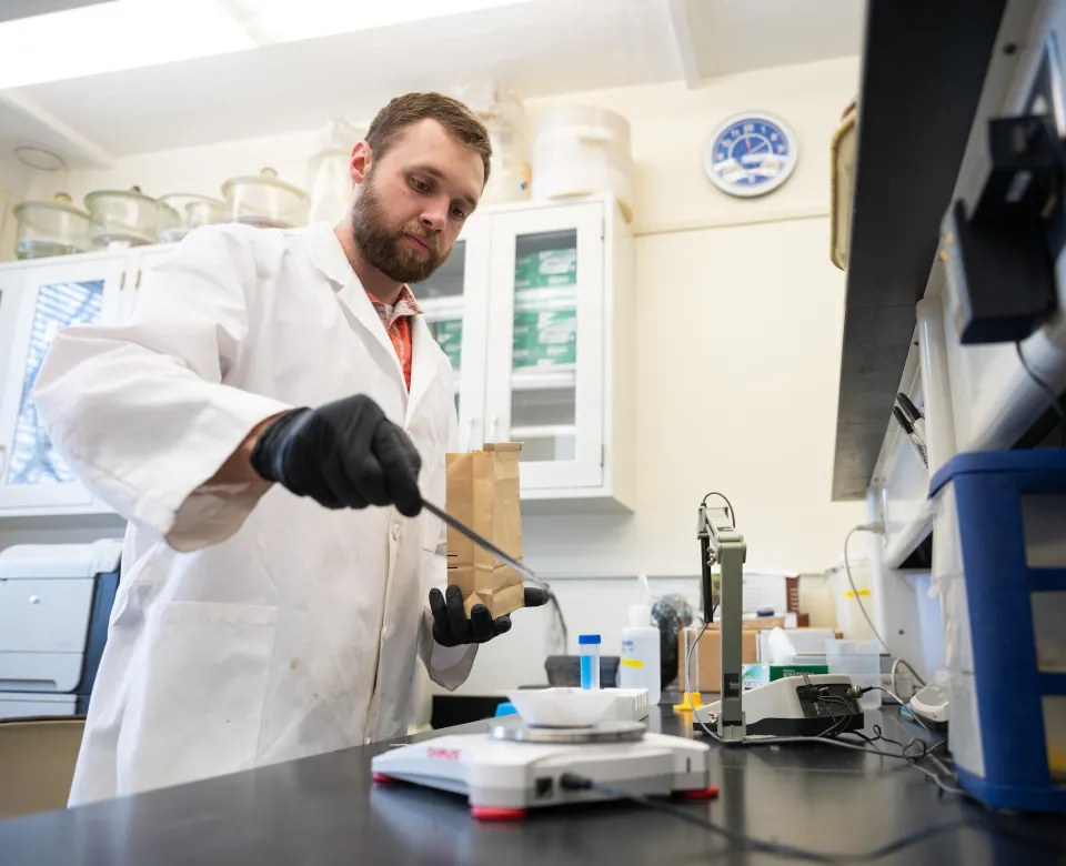 student weighing samples of dirt on a scale