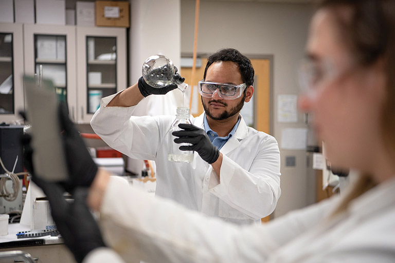 Chemistry student pouring chemical from beaker