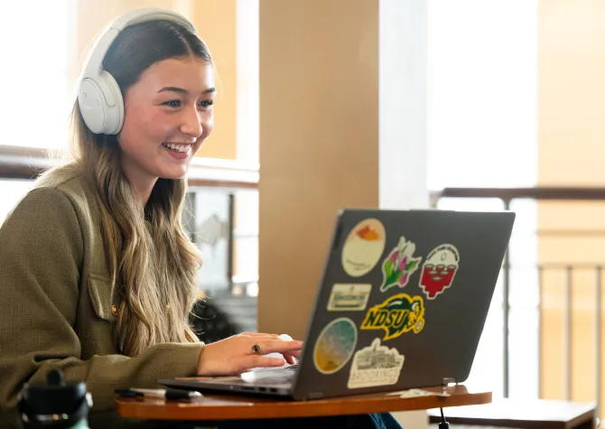 student wearing headphones and working on laptop
