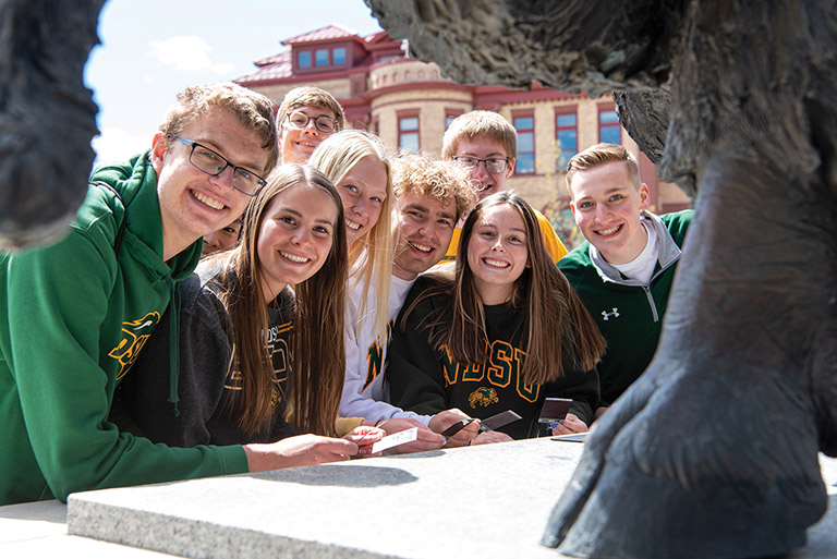 一群学生聚集在NDSU野牛雕像旁