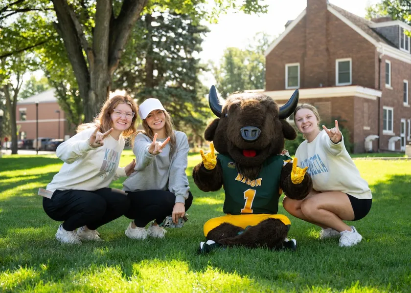 NDSU students and Thundar give the horns up.