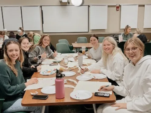 Six girls sitting at a table, smiling for the camera.