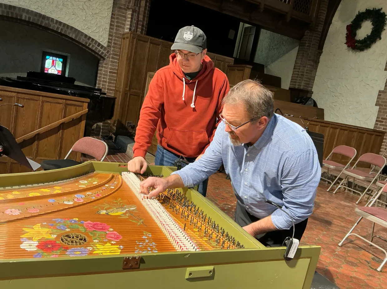 Piano technician Christian Heaford and NDSU student Zakk Volk installing new parts on the harpsichord.