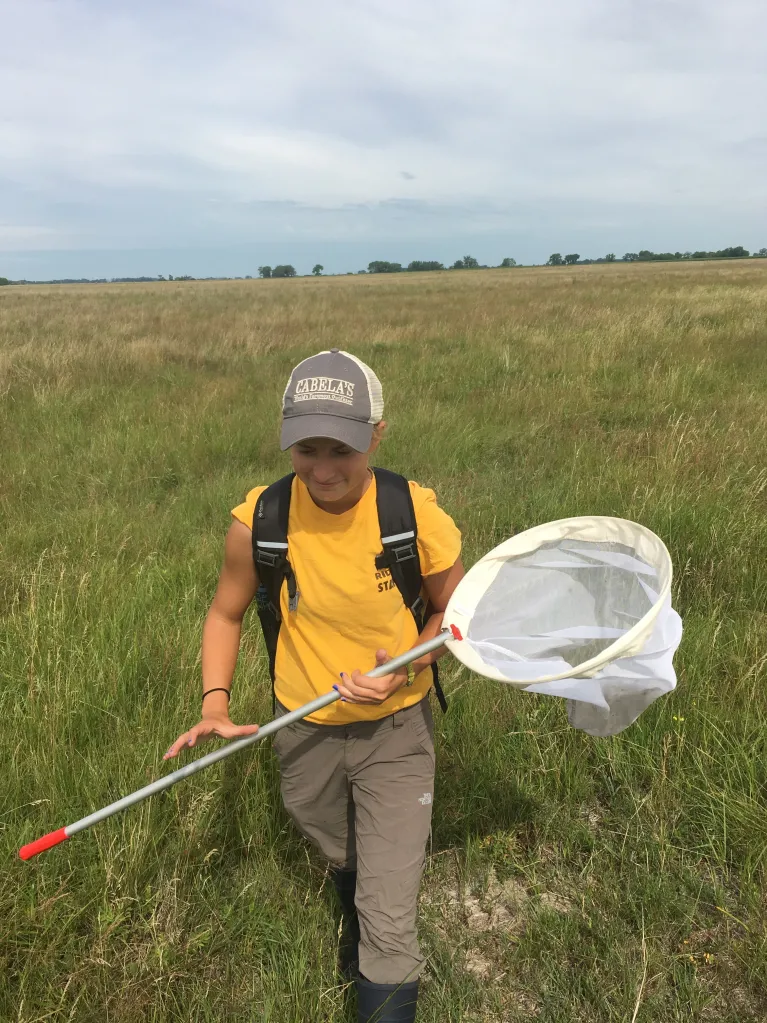 A person in a field with a bug net