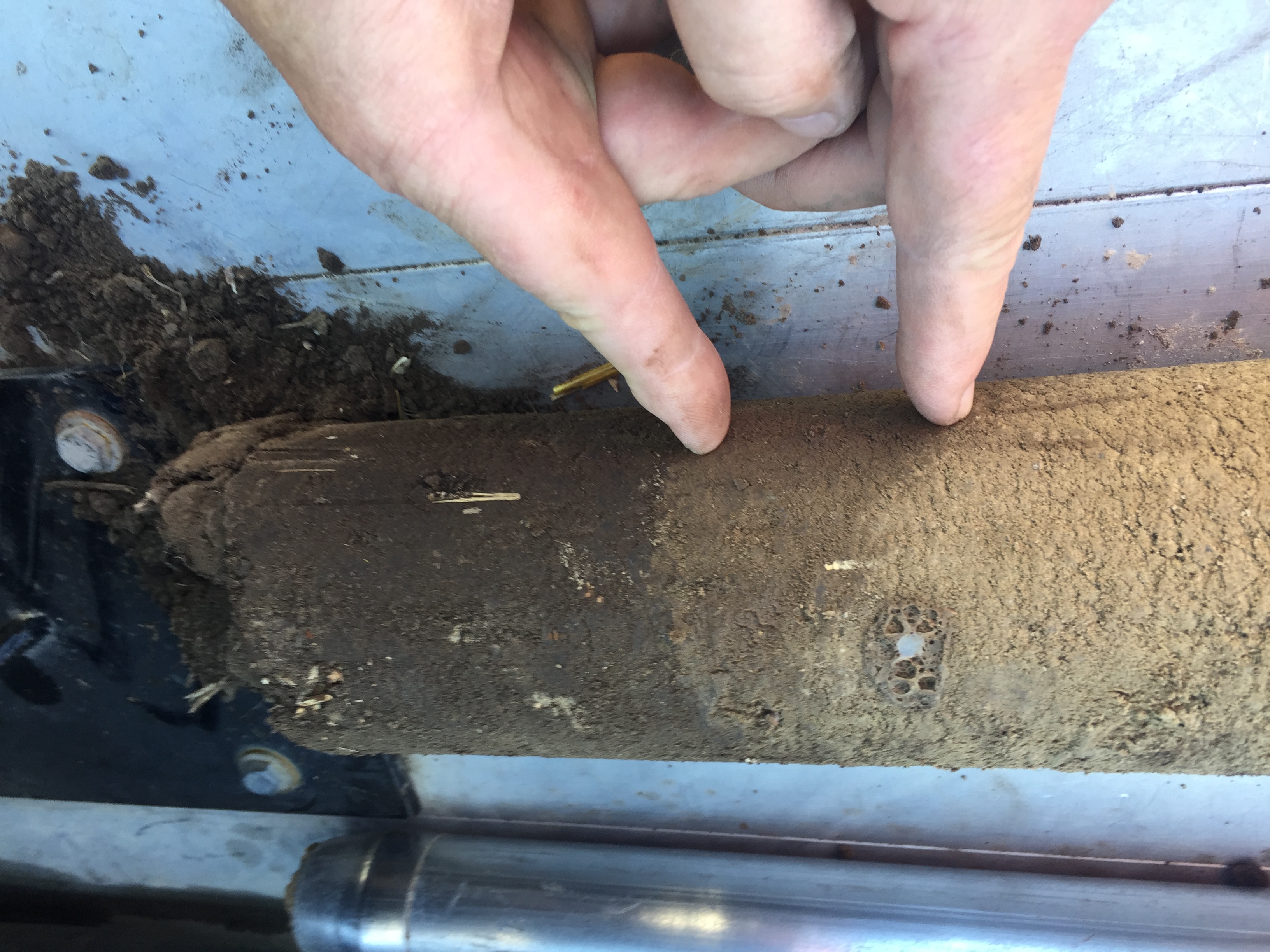 Two fingers point to the change in soil texture.