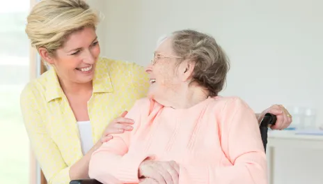 woman smiling at mom in sitting in a wheelchair