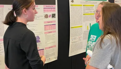 Student showing research poster to others