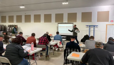 Sam Markell stands in front of a group of dry bean producers, explaining a table of data.