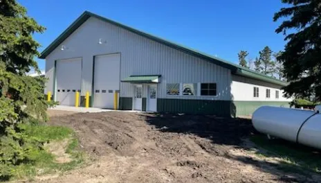 A white steel building with dark green roof and wainscoting.