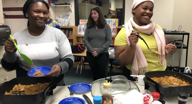 three women preparing food in electric skillets