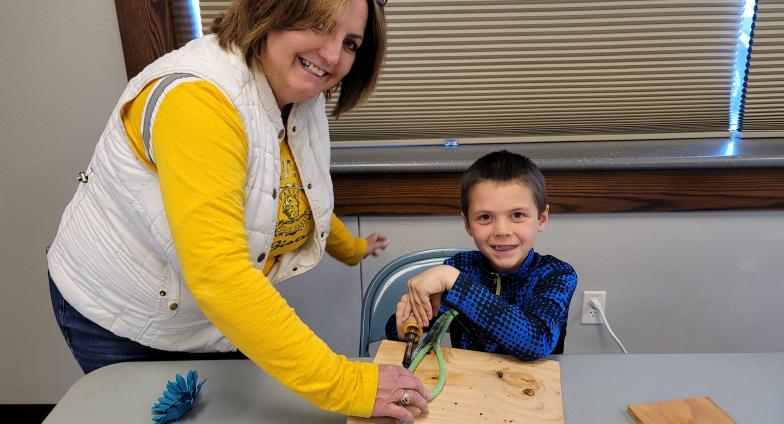 woman helping child with wood burning project