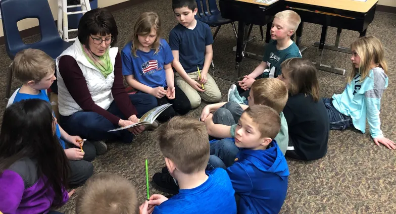 group of youth listening to a story read by woman