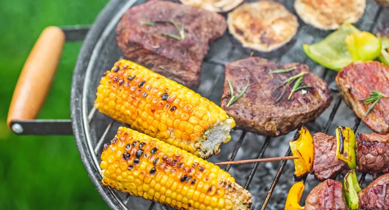 charcoal grill with corn on the cob, kabobs and steak 