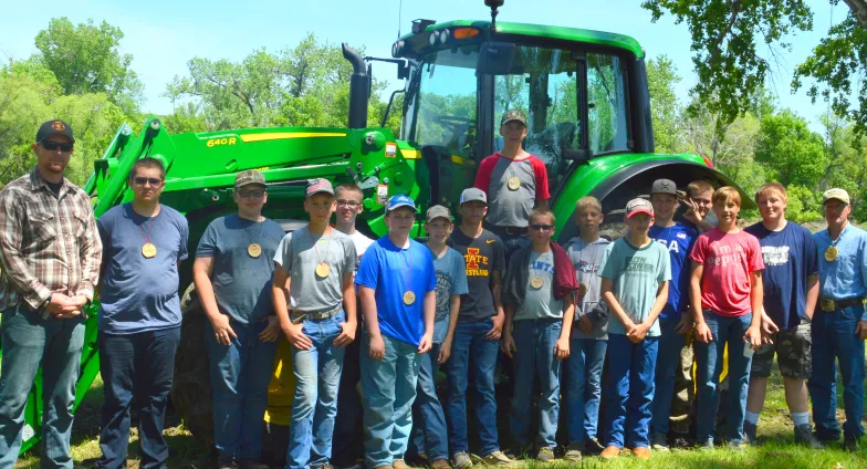 Teens posing in front of a green tractor 