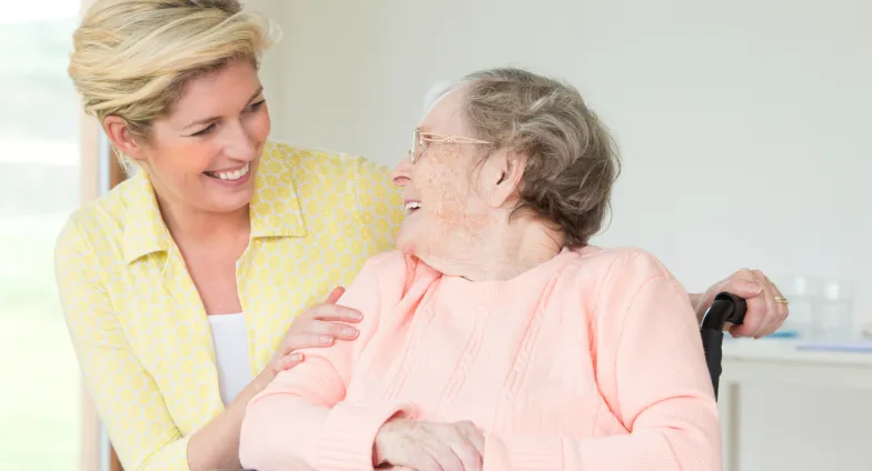 woman smiling at mom in sitting in a wheelchair