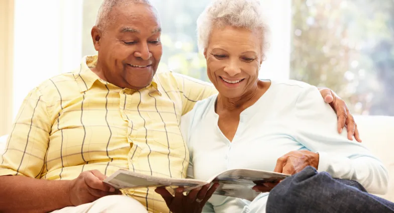 older adult couple reading magazine on couch