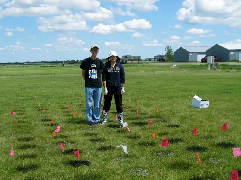 two students in a turf test field with flags for tagging