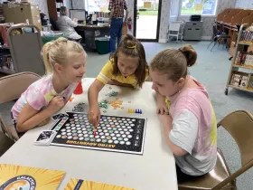 three young girls playing a STEM board game