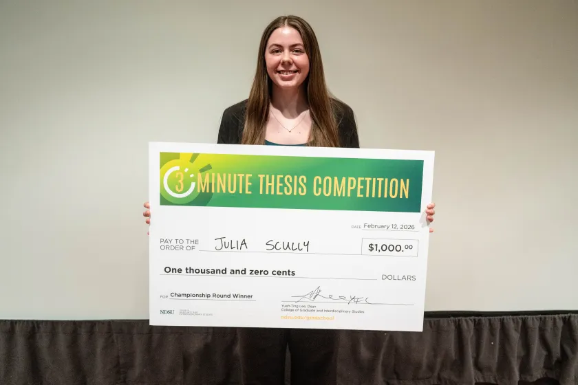 Julia Scully, a master’s student in coatings and polymeric materials, holds a check while posing for a photo.