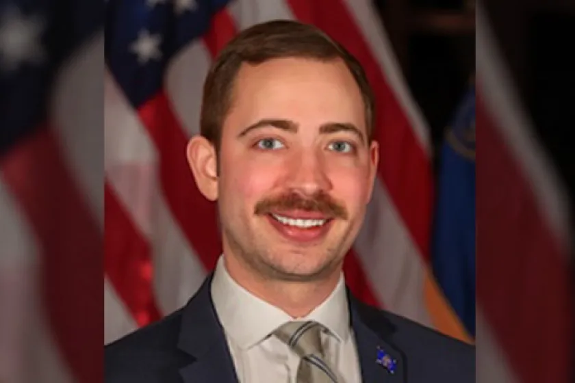 Conner Swanson wearing a suit in front of American flag