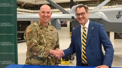 Col. Christopher Domitrovich and NDSU President David Cook shake hands after signing Memorandum of Agreement for student success