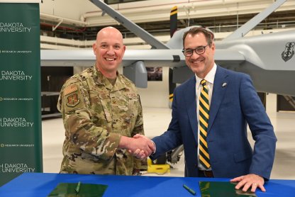 Col. Christopher Domitrovich and NDSU President David Cook shake hands after signing Memorandum of Agreement for student success