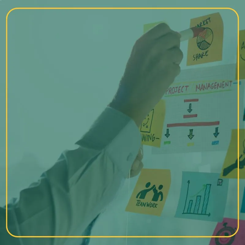 Person writing on a Post-It note on a white board
