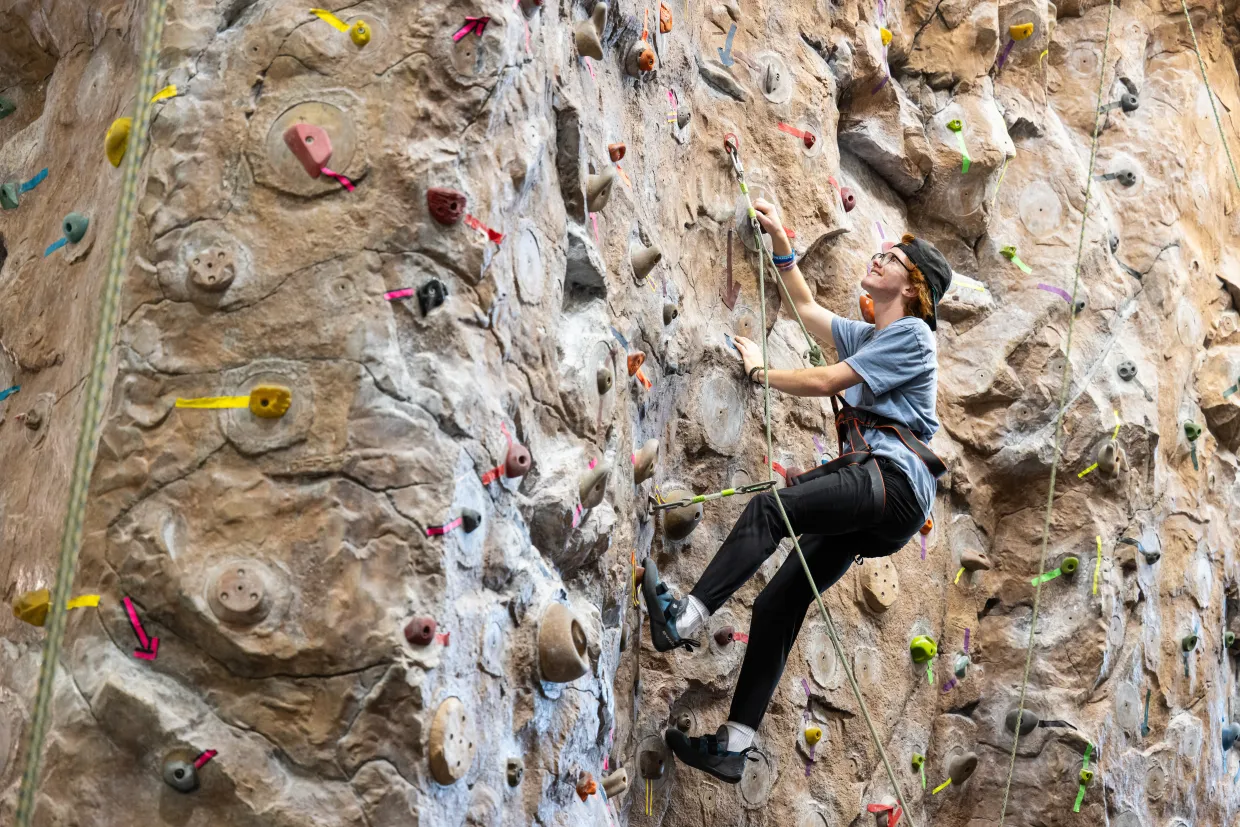 A student climbs the rock wall at the Wallman Wellness Center.