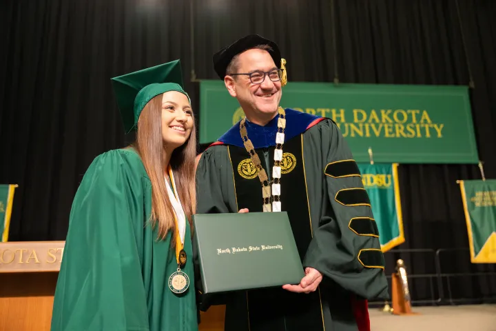 President Cook taking photo with graduate at commencement