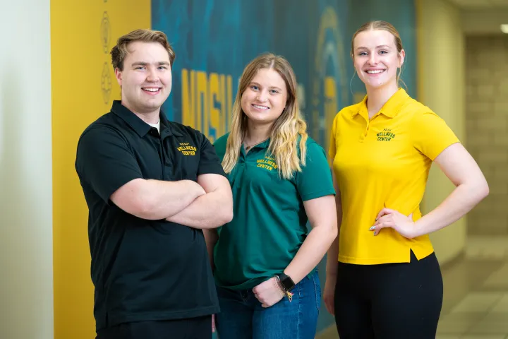 Three student employees smiling and standing together